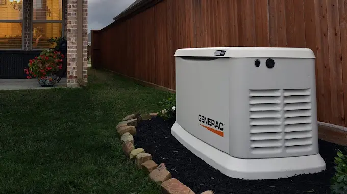 A home generator is sitting in the grass.